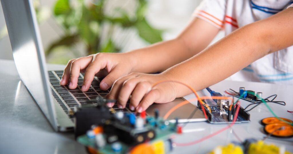 kids hands typing on keyboard, working on a robot, STEM assignment